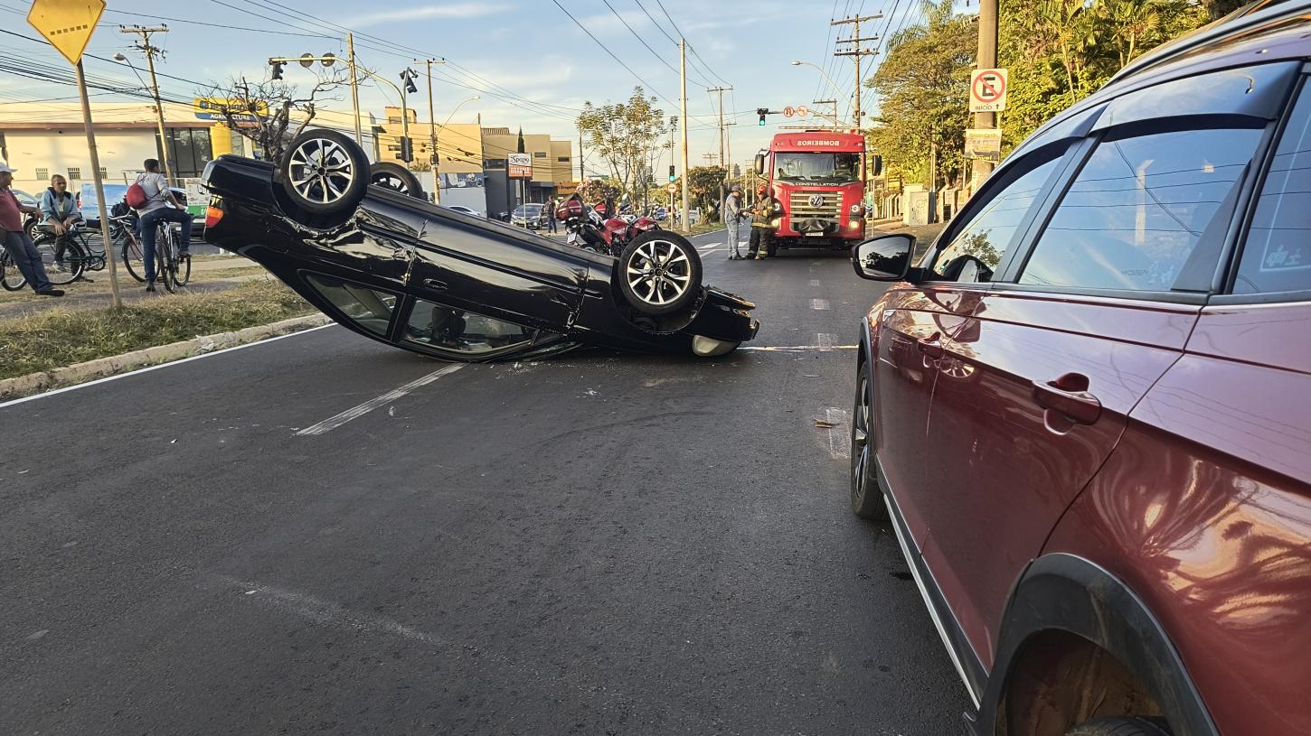 Motorista bate em carro estacionado e capota em avenida