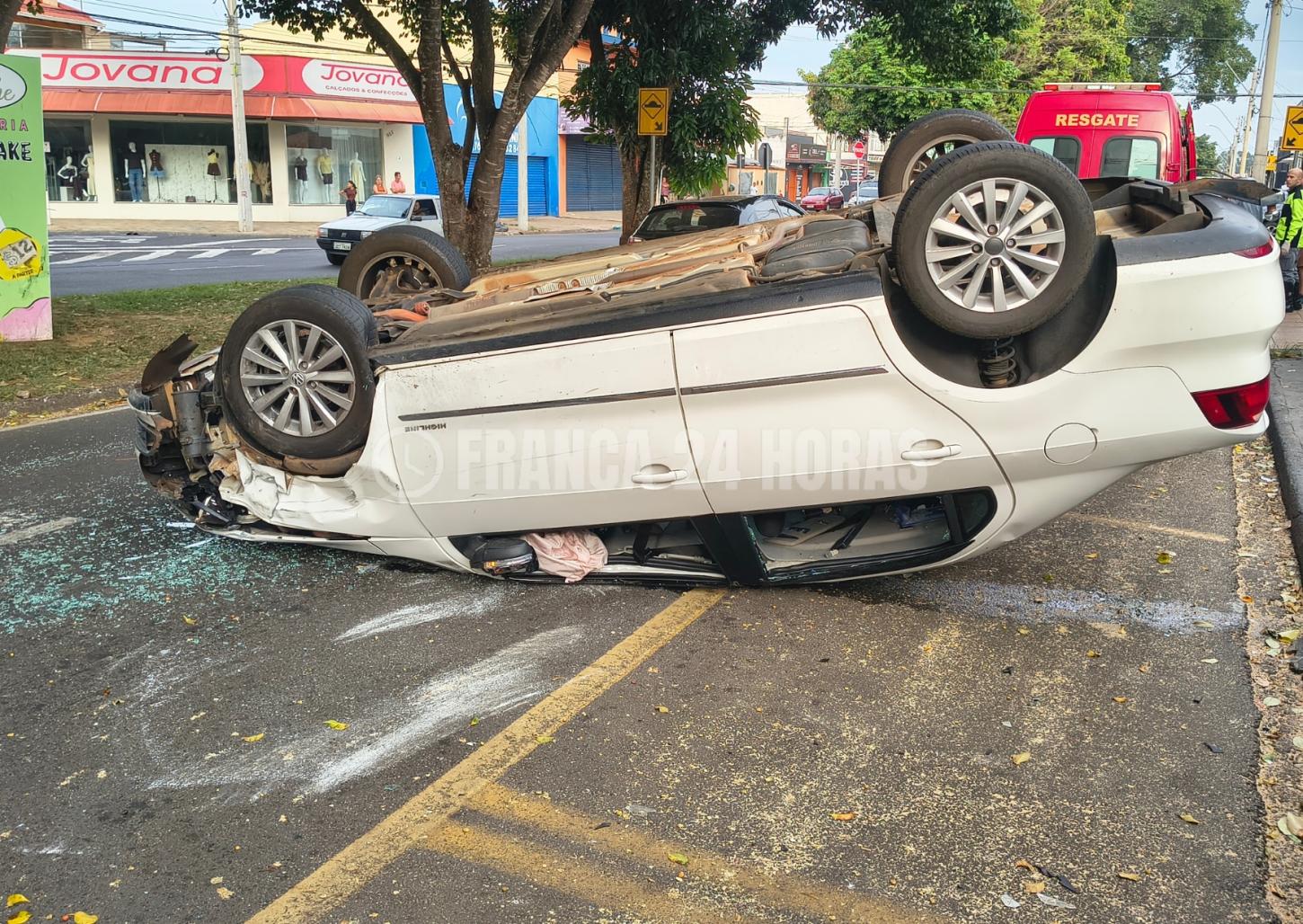Motorista bate em dois carros estacionados e capota em avenida