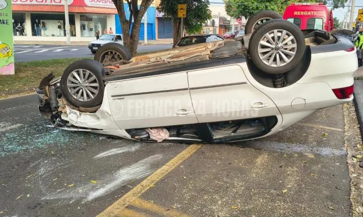 Motorista bate em dois carros estacionados e capota em avenida